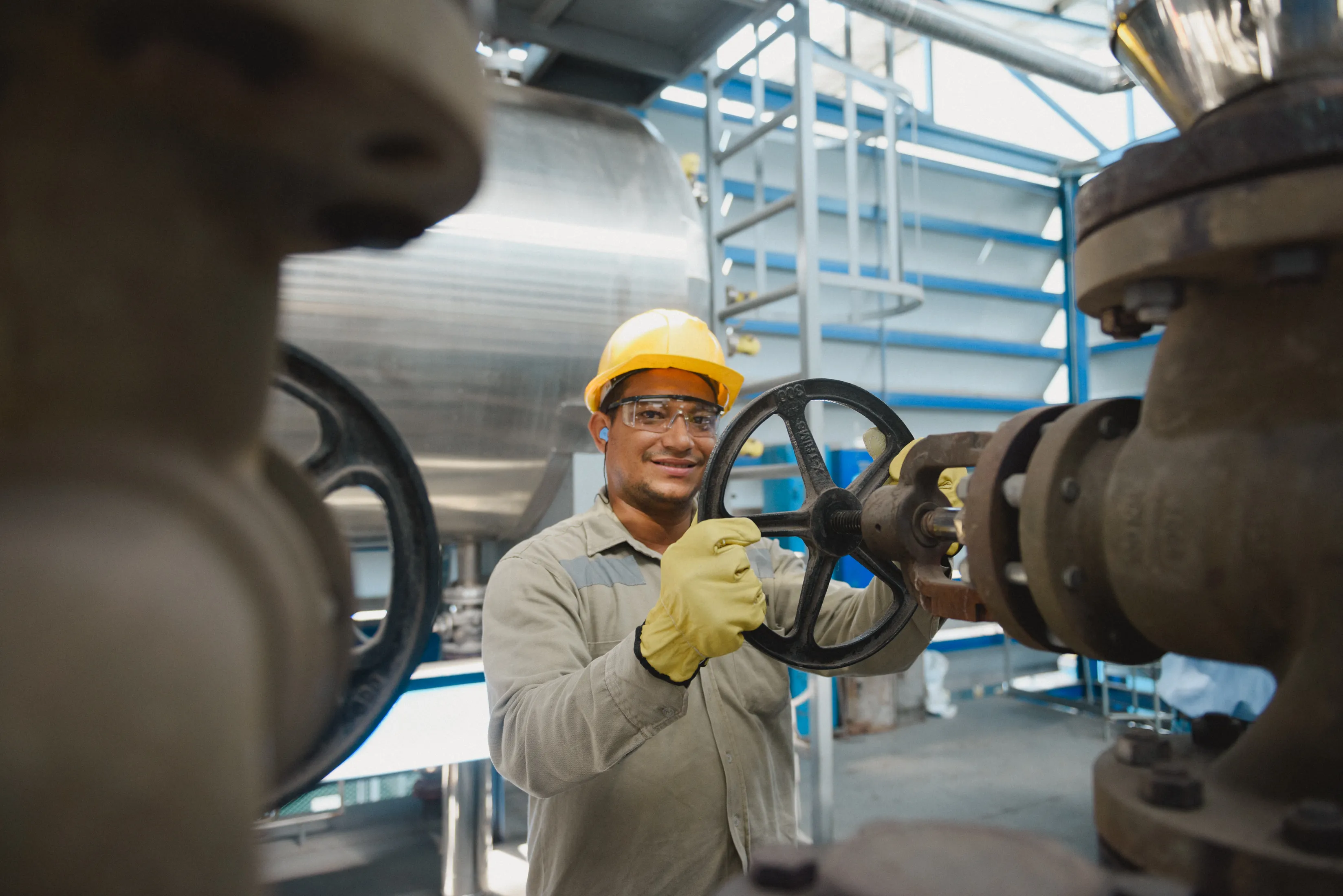 Técnico de planta operando una válvula en una instalación industrial.